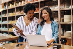 Deux jeunes commerçants utilisant un ordinateur portable dans leur magasin 