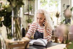 Une fleuriste note une commande au téléphone dans une boutique de fleurs