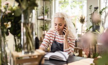 Une fleuriste note une commande au téléphone dans une boutique de fleurs