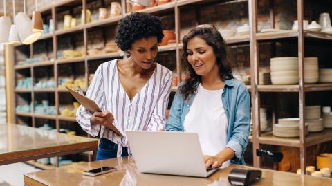 Deux jeunes commerçants utilisant un ordinateur portable dans leur magasin 