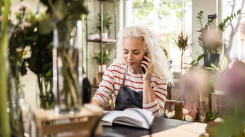 Une fleuriste note une commande au téléphone dans une boutique de fleurs