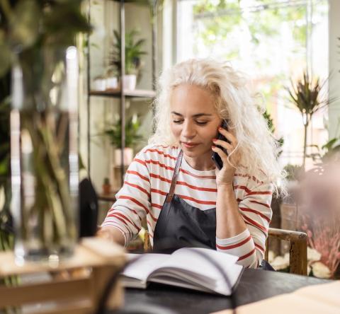 Une fleuriste note une commande au téléphone dans une boutique de fleurs